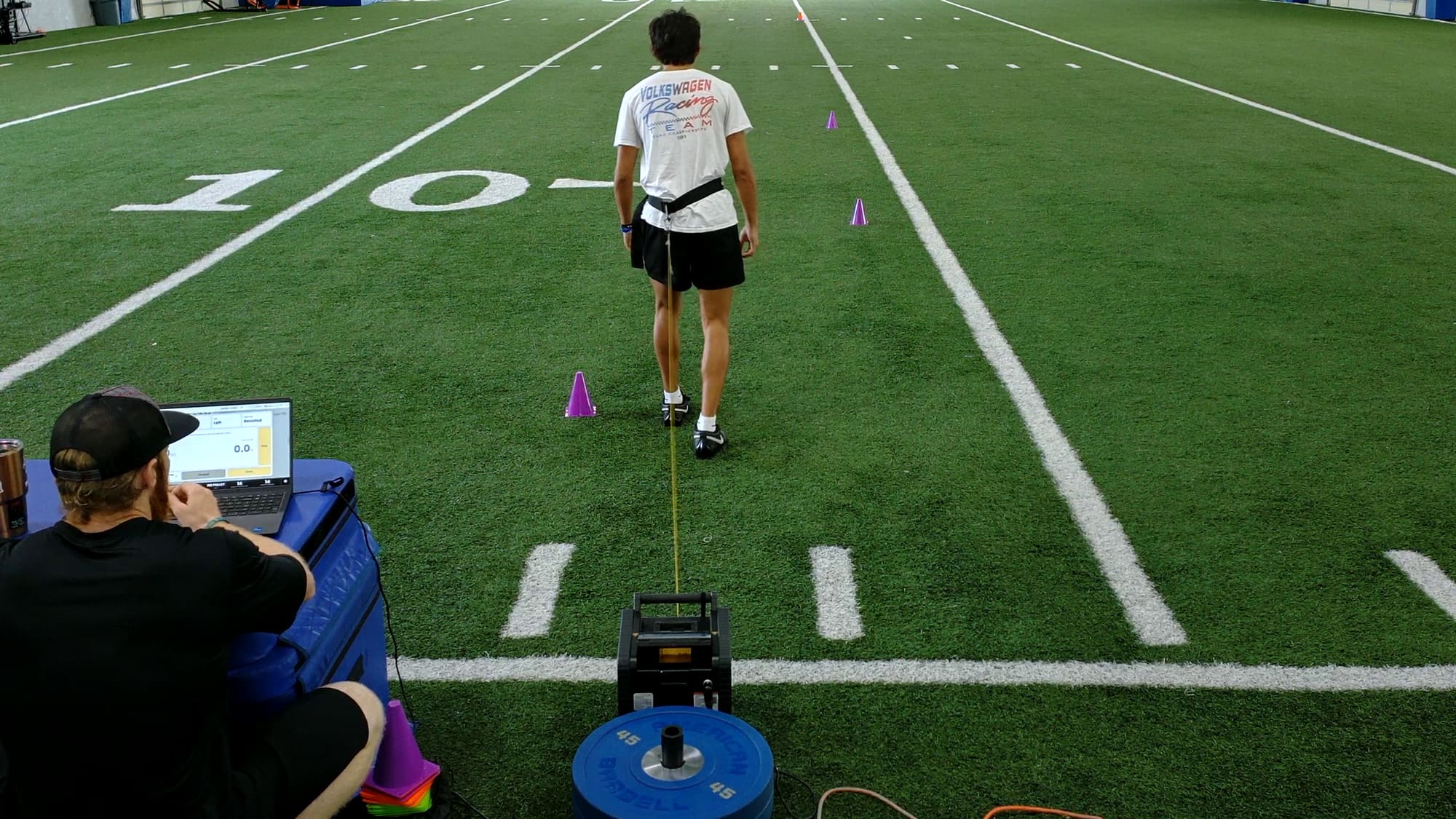 Athlete driving out of a resisted 1080 sprint on indoor turf