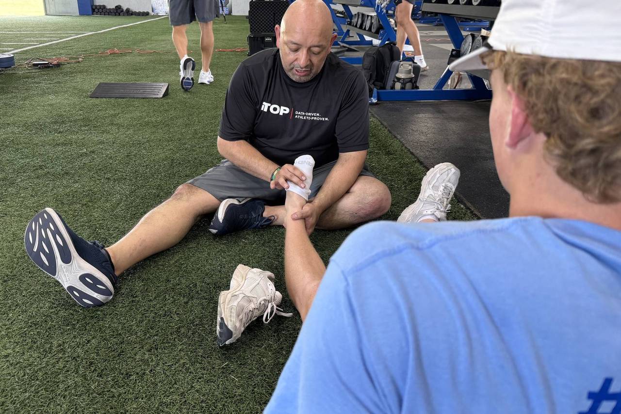 iTOP clinician working hands-on on an athlete's ankle on the turf